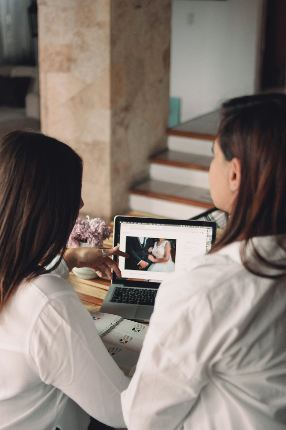 Two people review wedding photos on a laptop screen.
