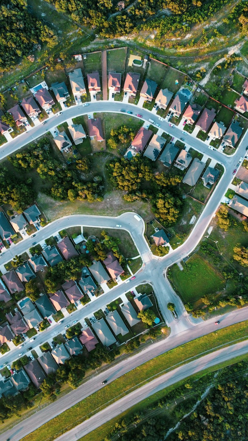 Suburban neighborhood with winding streets and houses among green trees.