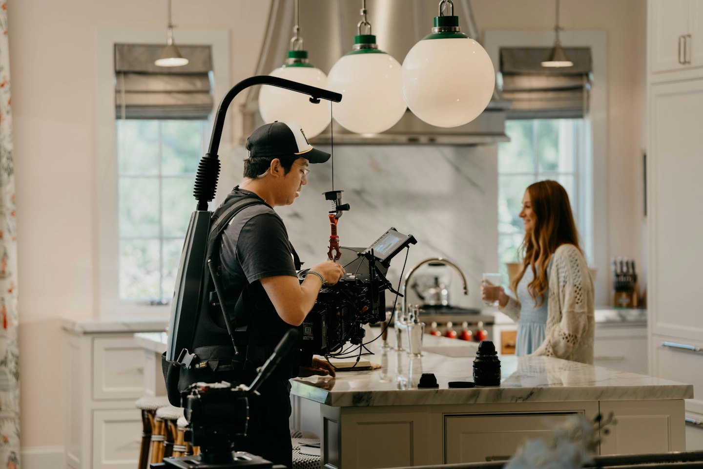 Man films woman in a modern kitchen.